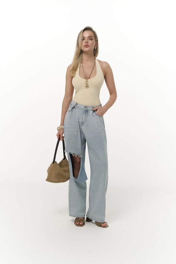 Wide-leg jeans with large unconventional cutouts revealing a darker inner denim layer.