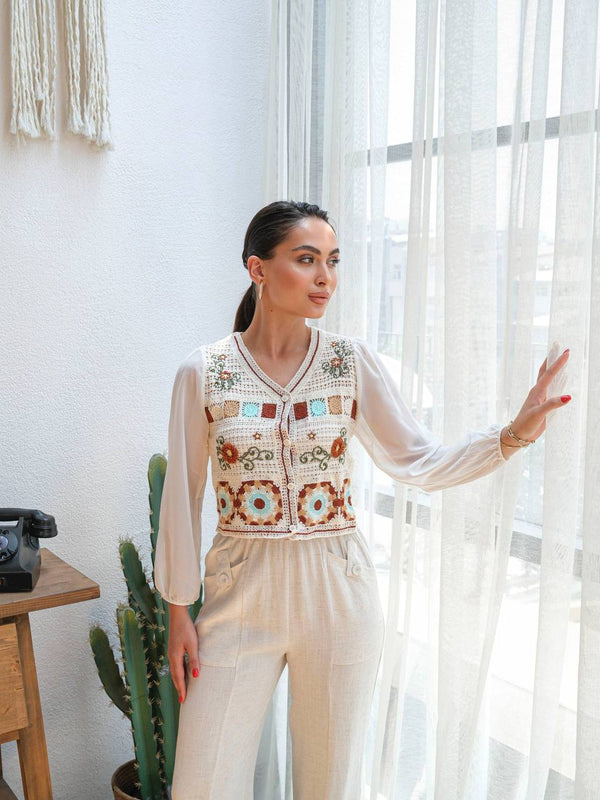 Elegant white outfit with a colorful embroidered vest, giving a chic and artistic vibe.